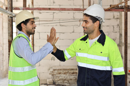 Two technician civil engineer or specialist inspector give high five celebrate successful together completed deal commitment at Industrial building site. Construction conceptの写真素材