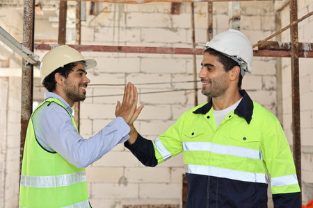 Two technician civil engineer or specialist inspector give high five celebrate successful together completed deal commitment at Industrial building site. Construction conceptの写真素材