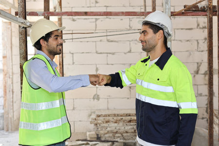 Two technician civil engineer or specialist inspector making fist bumping celebrate successful together completed deal commitment at Industrial building site. Construction conceptの写真素材