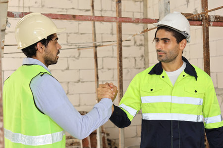 Two technician civil engineer or specialist inspector raising hand celebrate successful together completed deal commitment at Industrial building site. Construction conceptの写真素材