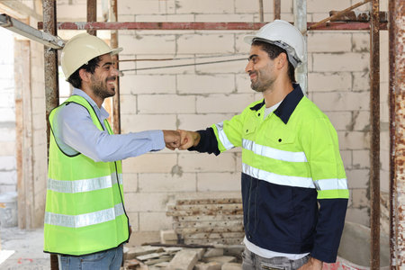 Two technician civil engineer or specialist inspector making fist bumping celebrate successful together completed deal commitment at Industrial building site. Construction conceptの写真素材