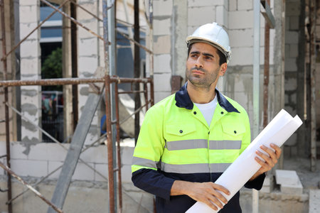 Caucasian technician civil engineer man or specialist inspector standing and planing real estate project work with blueprint while checking at Industrial building site. Construction conceptの写真素材