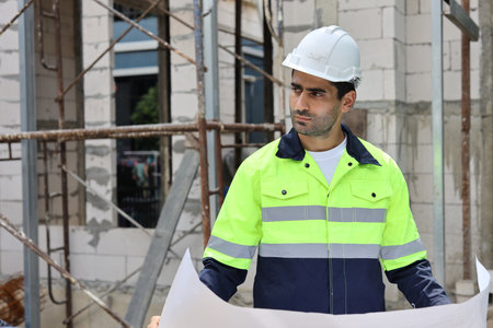 Caucasian technician civil engineer man or specialist inspector standing and planing real estate project work with blueprint while checking at Industrial building site. Construction conceptの写真素材