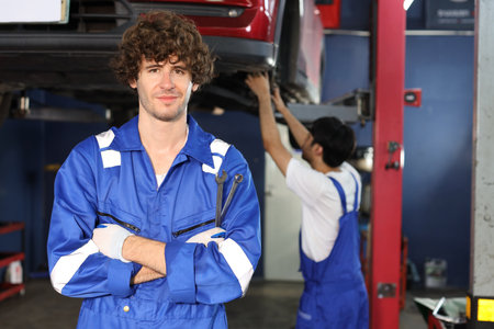 Caucasian technician engineer or worker man uniform standing and holding wrench checking maintenance a car service with confident at repair garage station. Concept of car center repair service.の写真素材