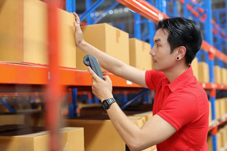 Warehouse workers asian man scanning barcode on large box package for delivery to production stock and inventory in retail warehouse logistics, distribution centerの写真素材