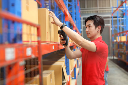 Warehouse workers asian man scanning barcode on large box package for delivery to production stock and inventory in retail warehouse logistics, distribution centerの写真素材