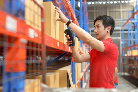 Warehouse workers asian man scanning barcode on large box package for delivery to production stock and inventory in retail warehouse logistics, distribution centerの写真素材