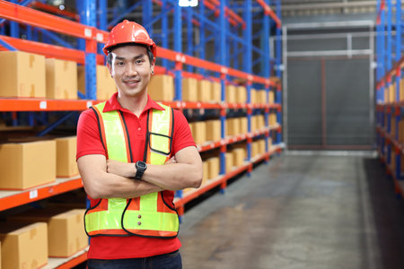Portrait of warehouse workers young asian man with hardhats and reflective jackets standing and crossed arms with happy smiling face and confident in retail warehouse logistics, distribution centerの写真素材