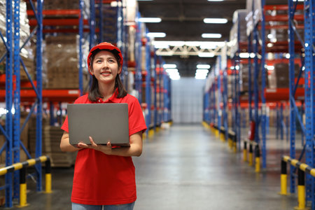 Portrait of warehouse workers young asian woman standing and using computer while looking away and controlling stock and inventory in retail warehouse logistics, distribution centerの写真素材