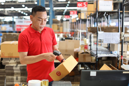 Warehouse workers man using computer, walkie talkie radio and cardboard for controlling stock and payment in retail warehouse logistics, distribution centerの写真素材