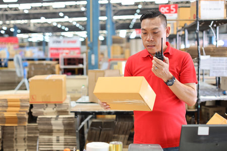 Warehouse workers man using computer, walkie talkie radio and cardboard for controlling stock and payment in retail warehouse logistics, distribution centerの写真素材