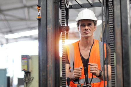 Young architect men or forklift driver sitting in vehicle with confident while looking at camera at heavy industry manufacturing factory.の写真素材