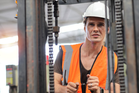 Young architect men or forklift driver sitting in vehicle with confident while looking at camera at heavy industry manufacturing factory.の写真素材
