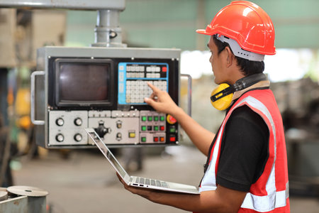 Technician engineer or worker in protective uniform standing and using computer while controlling...