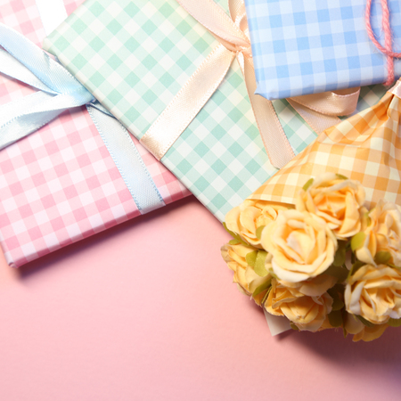 Check pattern colorful gift boxes with flower bouquet on pink backgroundの写真素材