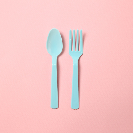 Blue plastic fork and spoon isolated on pink backgroundの写真素材