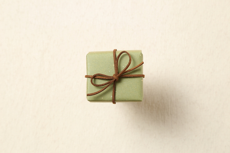 Green gift box isolated on beige fabric backgroundの写真素材