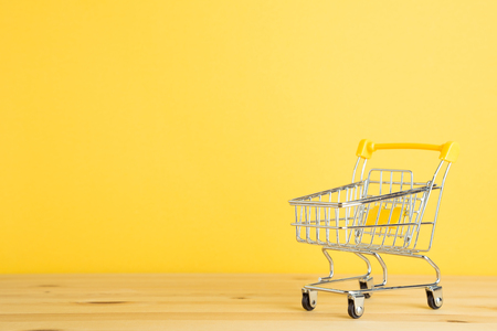 Shopping cart on wooden table with yellow backgroundの写真素材