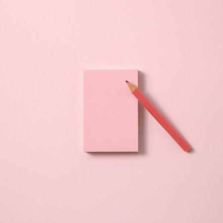 Pink memo note pad and pink colored pencil on pink backgroundの写真素材