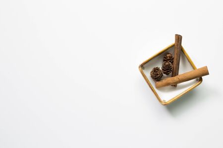 Pine cones and cinnamon sticks in a bowl on white background. Autumn conceptの写真素材