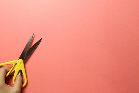 Scissors with hand on pink background