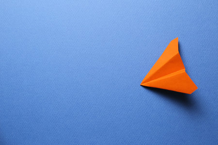 Orange paper plane on blue background