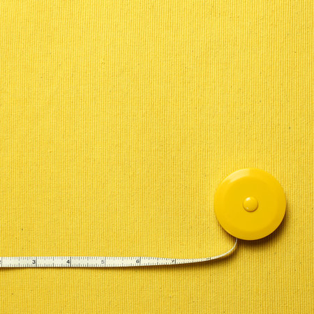 Tape measure on yellow fabric background