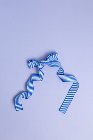 Striped pattern blue bow ribbon isolated on purple background
