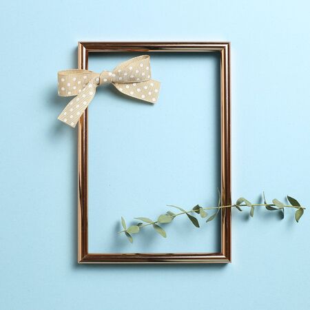 Empty photo frame with eucalyptus leaves and ribbon on sky blue background. top view, copy spaceの写真素材