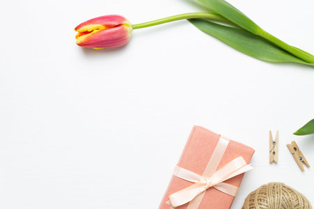 Gift box with red tulip flower on white background. Floral composition, flat lay, top view, copy...