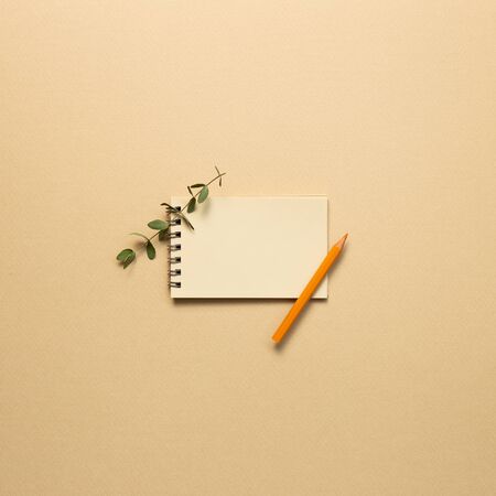 Empty kraft notepad with colored pencil on beige background. top viewの写真素材