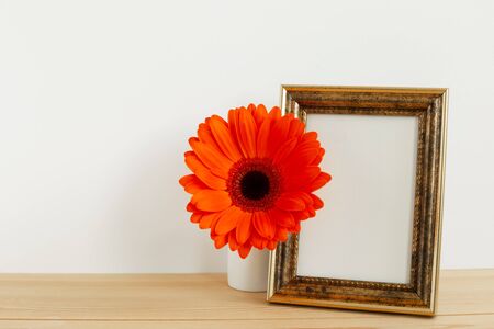 Photo frame with orange gerbera flower on wooden tableの写真素材