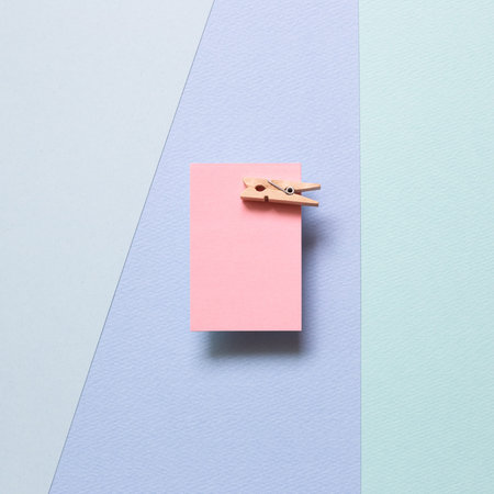 Pink memo paper, sticky notes with wooden clip on blue background. top view, copy space