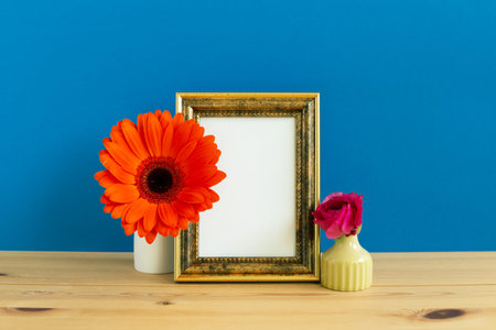 Photo frame with flower decoration on wooden table with blue background. copy space