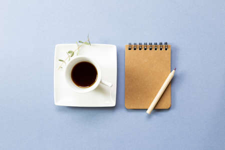 Notebook and black coffee on blue background. flat lay, top view, copy space. Work and study placeの写真素材