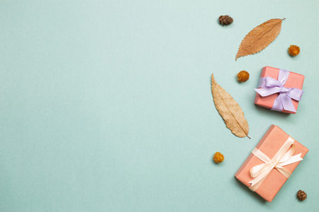 Gift boxes with autumn dry leaves on green background. flat lay, top view, copy space