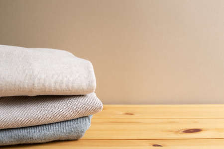 Pile of warm sweater clothes on wooden table. Autumn and winter concept. with copy spaceの写真素材