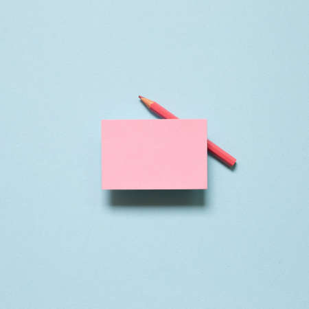 Pink memo paper, sticky notes with colored pencil on blue background. top view, copy spaceの写真素材