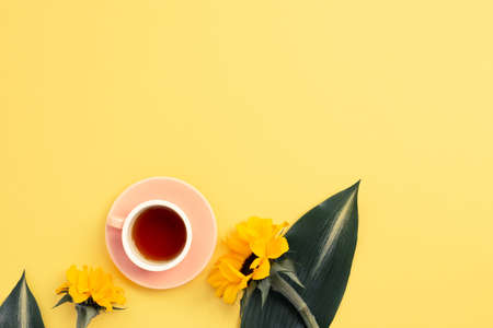 Cup of black tea with Yellow sunflowers on yellow background. top view, copy spaceの写真素材