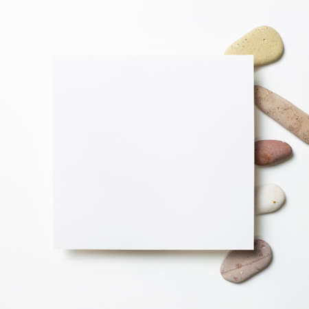 White memo pad, empty paper with pebble stones on white background. flat lay, top view, copy spaceの写真素材