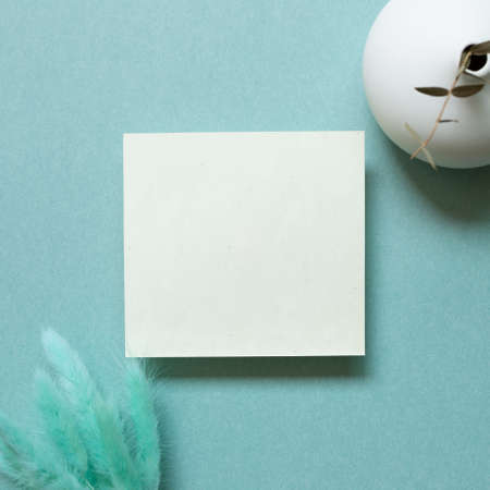 Blank memo pad, empty paper with hares tail grass (Lagurus ovatus) dry flowers and eucalyptus flowerpot on green background. flat lay, top view, copy spaceの写真素材