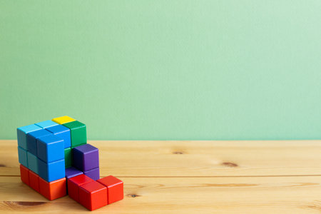 Colorful cube puzzle blocks on wooden desk with green background. Problem solving, creative idea...