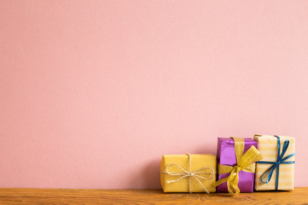 Colorful gift boxes on wooden table. Pink background copy space