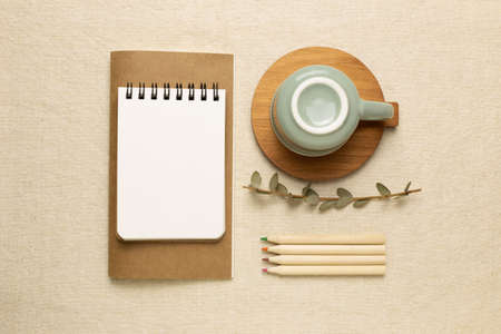 Work and study place. Notebooks, mug cup, colored pencils on beige fabric background. flat lay, top view, copy spaceの写真素材