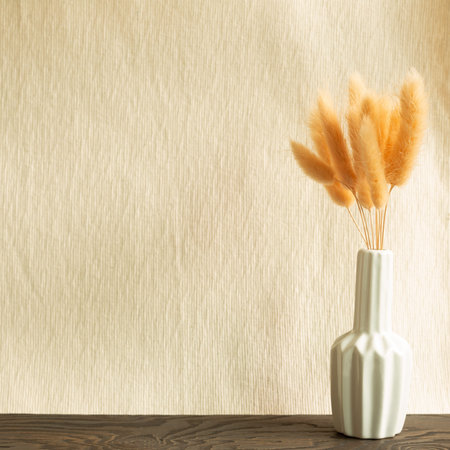 Vase of pink hares tail grass (Lagurus ovatus) dry flowers on wooden table. Beige fabric backgroundの写真素材