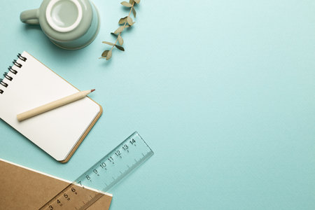 Notebook, mug cup, pencil, ruler on sky blue background. flat lay, top view, copy space. Work and study placeの写真素材