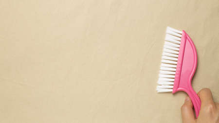 Cleaning housework concept. Pink broom on beige fabric background. flat lay, top view, copy spaceの写真素材