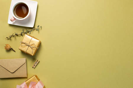 Gift box, cup of tea, dry flower on khaki green background. flat lay, top view, copy spaceの写真素材