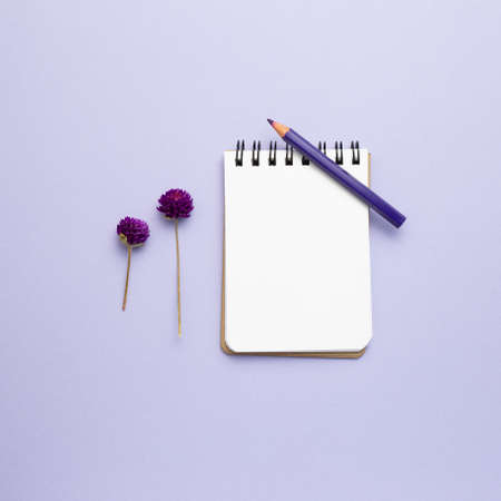 Empty notebook, colored pencil, dry flowers on purple background. top view, copy spaceの写真素材