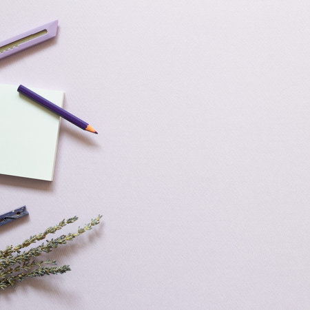 Notepad, cutter, colored pencil, clip, lavender flowers on purple background. flat lay, top view,...